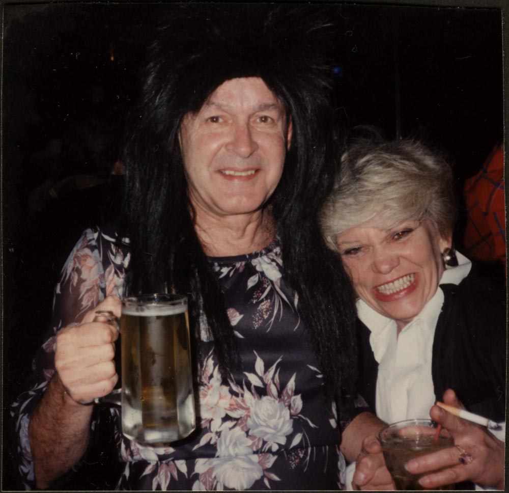 Two people smiling and holding mugs of beer