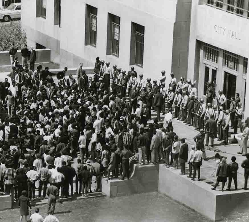 A crowd gathers on the steps of city hall
